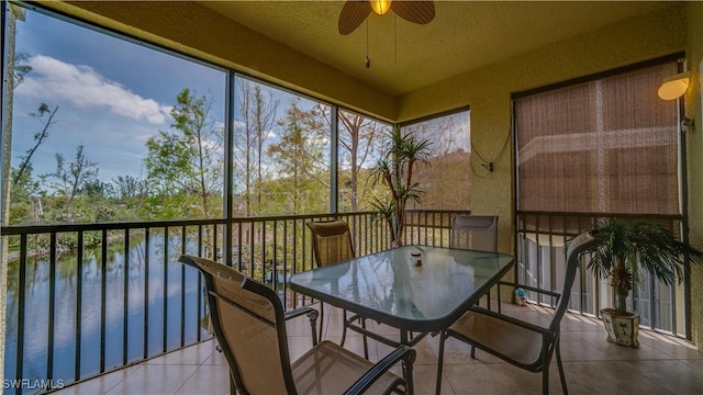 sunroom featuring ceiling fan and a water view