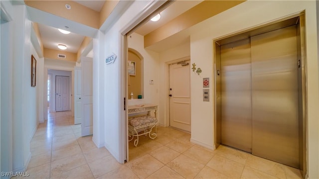 corridor featuring light tile patterned floors and elevator