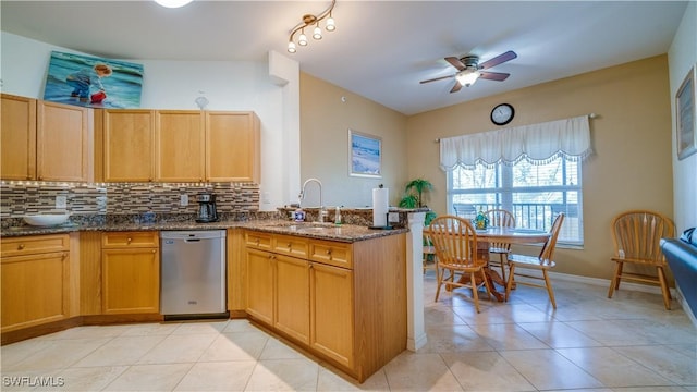 kitchen featuring sink, stainless steel dishwasher, dark stone countertops, light tile patterned floors, and tasteful backsplash