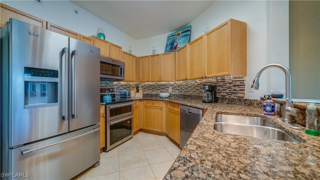 kitchen with backsplash, dark stone countertops, sink, and appliances with stainless steel finishes