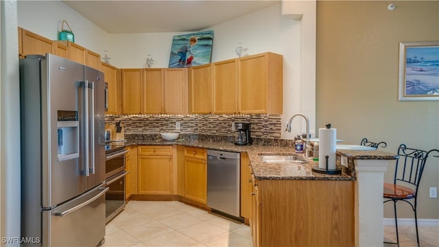 kitchen featuring sink, stainless steel appliances, kitchen peninsula, dark stone counters, and decorative backsplash