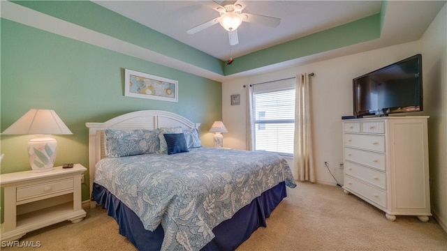 carpeted bedroom featuring a raised ceiling and ceiling fan