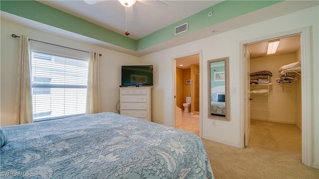 carpeted bedroom featuring ensuite bathroom, ceiling fan, a walk in closet, and a closet