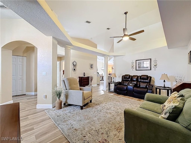 living room featuring ceiling fan, lofted ceiling, decorative columns, and light hardwood / wood-style flooring