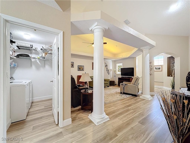 living room featuring light hardwood / wood-style floors, decorative columns, and washing machine and dryer