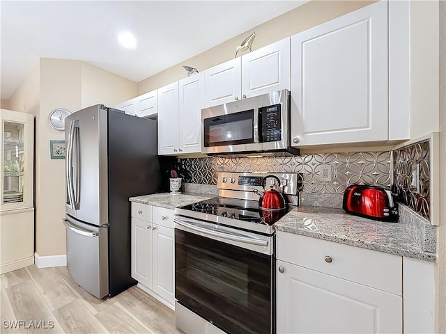 kitchen with white cabinetry, light stone countertops, and appliances with stainless steel finishes