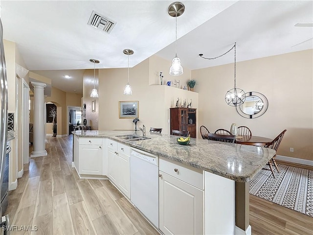 kitchen with ornate columns, dishwasher, white cabinetry, sink, and a center island with sink