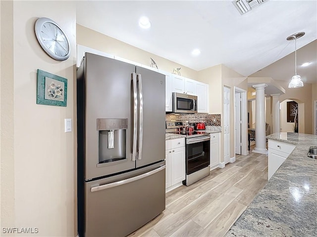 kitchen with stainless steel appliances, decorative columns, and white cabinets