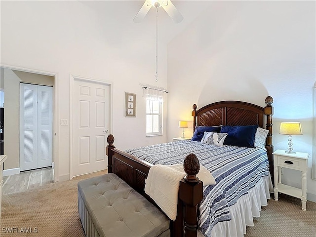 bedroom featuring a high ceiling, light colored carpet, and ceiling fan