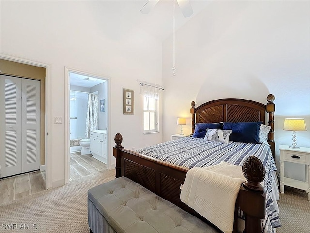 bedroom featuring ceiling fan, a towering ceiling, ensuite bathroom, and light carpet