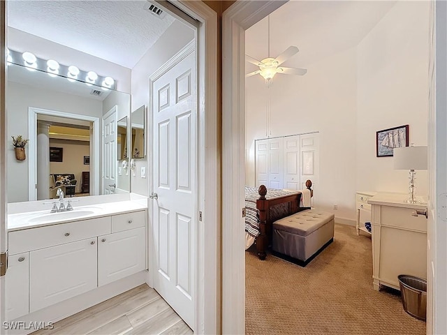 bathroom with ceiling fan, vanity, and a textured ceiling