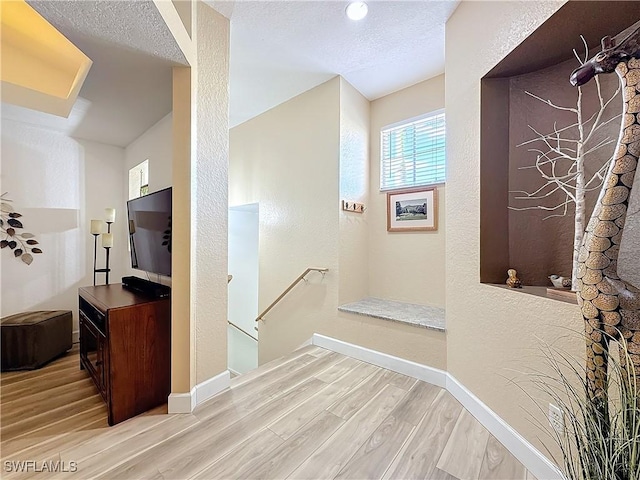 hallway featuring a textured ceiling and light wood-type flooring