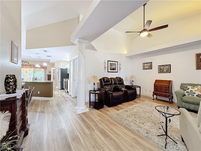 living room featuring a towering ceiling, light hardwood / wood-style flooring, decorative columns, and ceiling fan