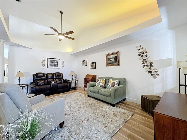 living room featuring ceiling fan, vaulted ceiling, decorative columns, and light wood-type flooring