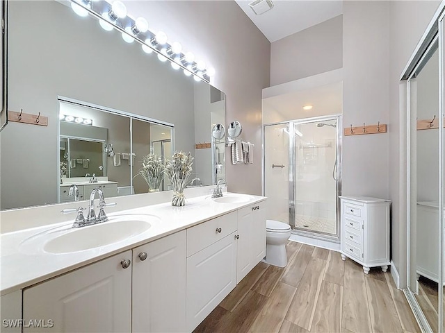 bathroom featuring wood-type flooring, toilet, a shower with shower door, and vanity