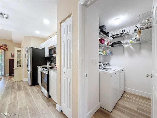 clothes washing area with light hardwood / wood-style floors and independent washer and dryer