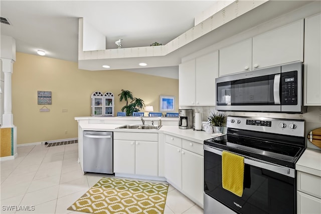 kitchen with kitchen peninsula, sink, light tile patterned flooring, appliances with stainless steel finishes, and white cabinets