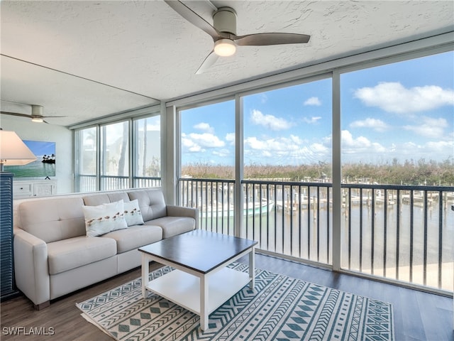 sunroom with ceiling fan, a healthy amount of sunlight, and a water view