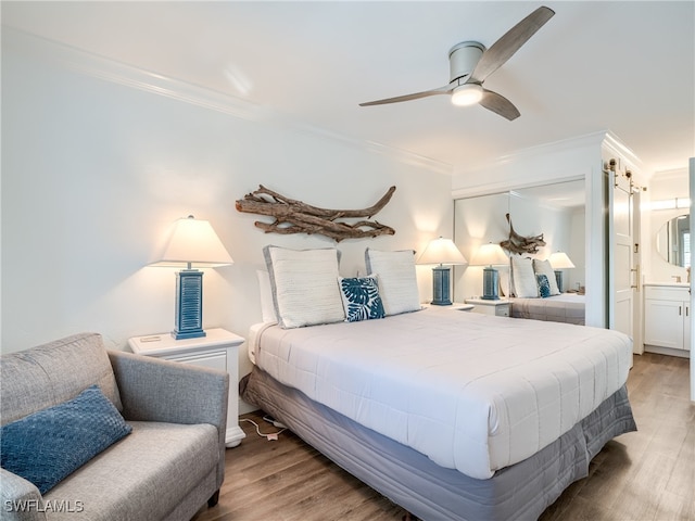 bedroom featuring hardwood / wood-style floors, ensuite bath, ceiling fan, and crown molding