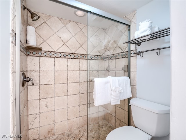 bathroom with a shower with shower door and toilet