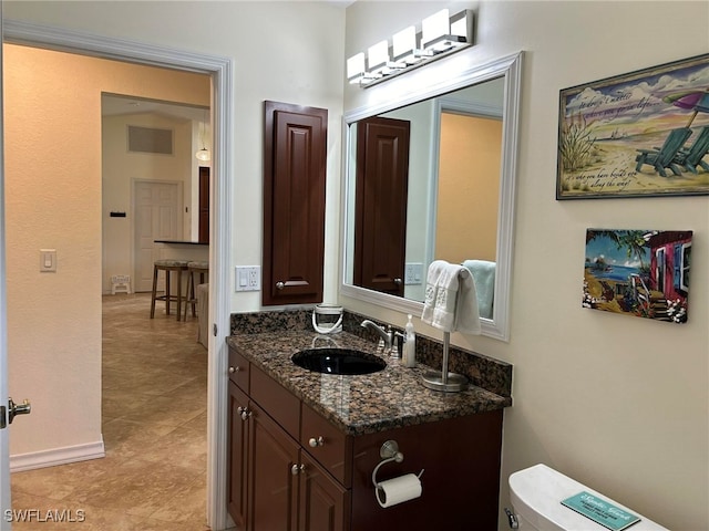 bathroom with toilet, vanity, and tile patterned floors