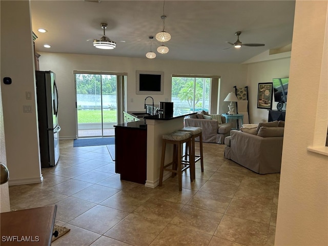 kitchen featuring a healthy amount of sunlight, decorative light fixtures, a kitchen breakfast bar, and stainless steel fridge