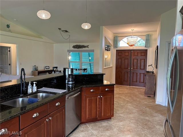 kitchen featuring dark stone counters, stainless steel appliances, sink, and pendant lighting