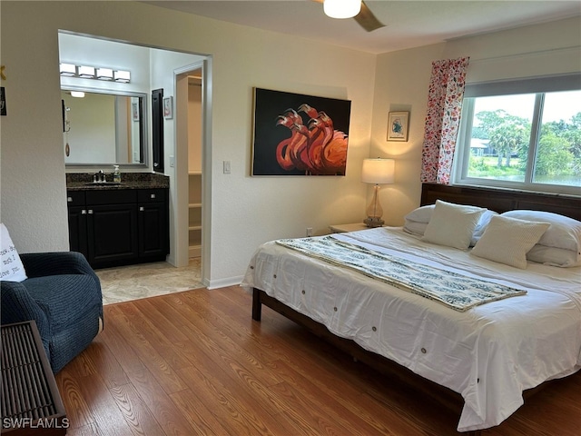 bedroom featuring light hardwood / wood-style flooring, sink, connected bathroom, and ceiling fan