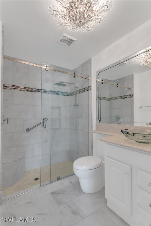 bathroom with toilet, vanity, a chandelier, and a shower with door