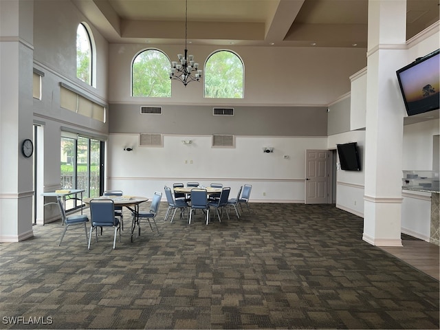 dining room featuring plenty of natural light, dark carpet, and a towering ceiling