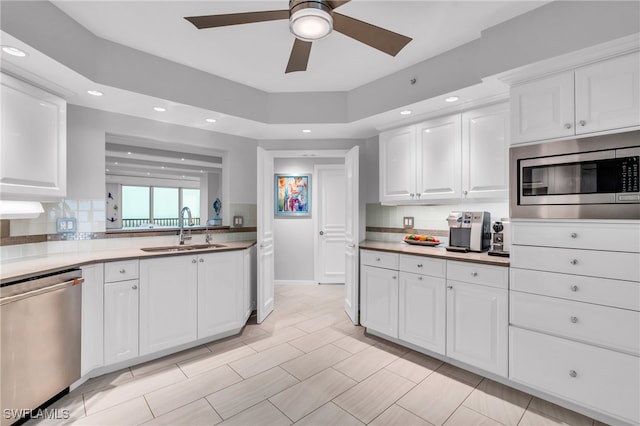 kitchen with white cabinetry, sink, decorative backsplash, appliances with stainless steel finishes, and ceiling fan