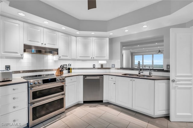 kitchen with decorative backsplash, appliances with stainless steel finishes, ceiling fan, sink, and white cabinetry