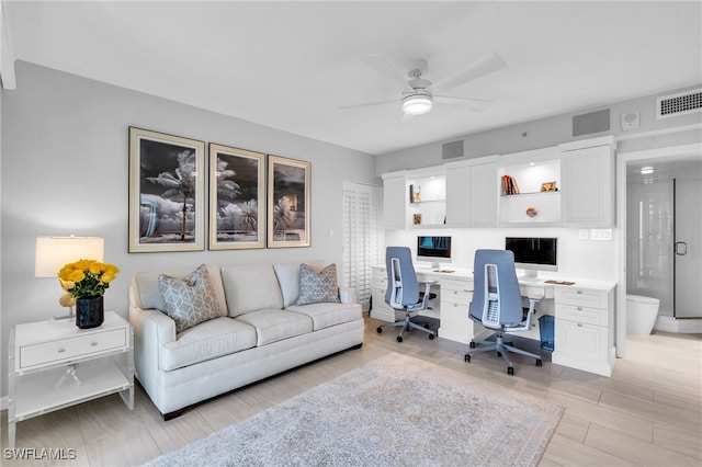 office area featuring light wood-type flooring, built in desk, and ceiling fan