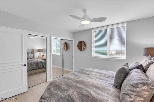 bedroom with multiple windows, ceiling fan, and multiple closets