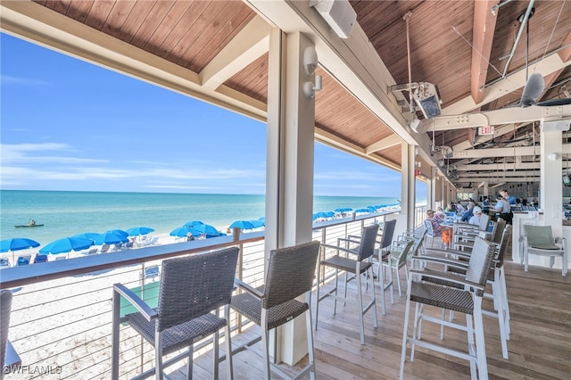 wooden terrace featuring a water view and a view of the beach