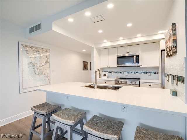 kitchen with sink, kitchen peninsula, appliances with stainless steel finishes, tasteful backsplash, and dark hardwood / wood-style flooring