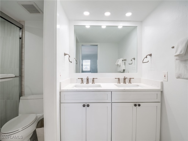 bathroom with a shower with door, vanity, and toilet