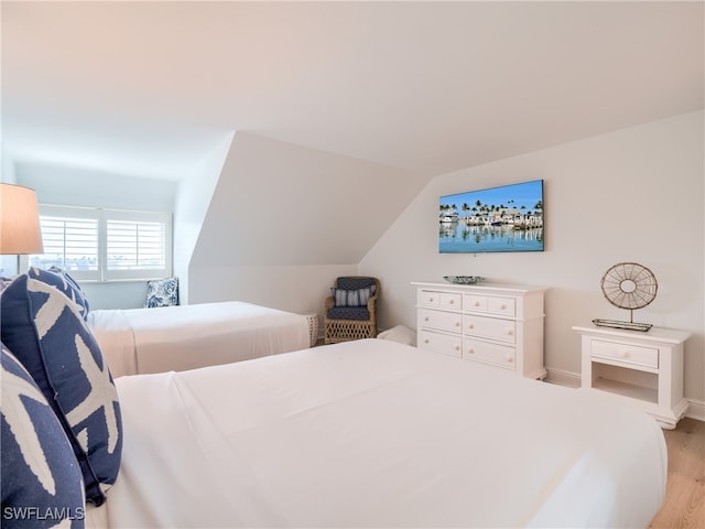 bedroom with vaulted ceiling and light hardwood / wood-style floors