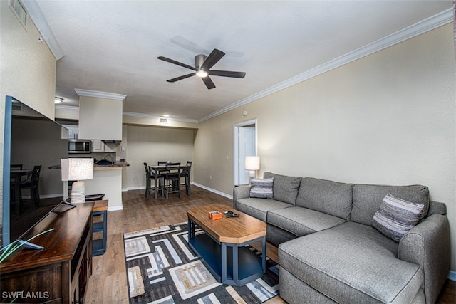 living room with dark hardwood / wood-style floors, ceiling fan, and ornamental molding