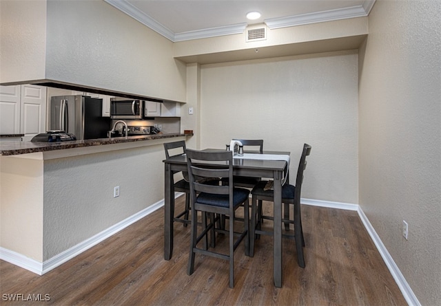 dining area with dark hardwood / wood-style flooring, crown molding, and sink