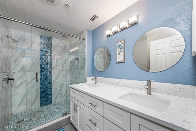 bathroom with vanity, a shower with door, and a textured ceiling