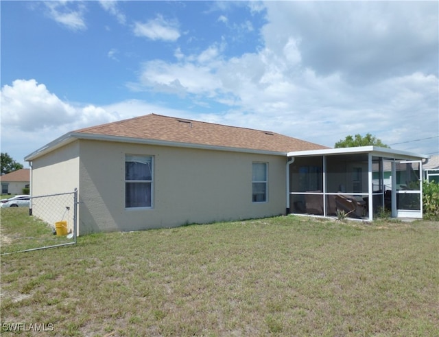 back of house featuring a lawn and a sunroom