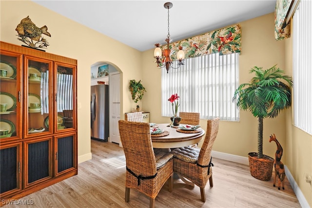 dining space featuring light wood-type flooring and an inviting chandelier