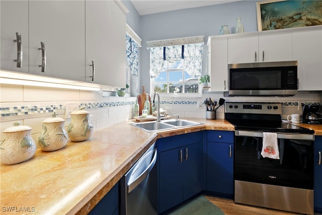 kitchen featuring blue cabinets, white cabinets, appliances with stainless steel finishes, and sink