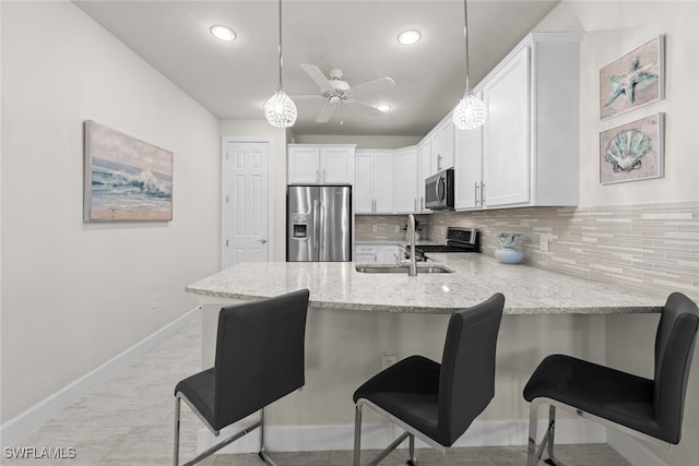 kitchen with a kitchen breakfast bar, white cabinets, pendant lighting, and appliances with stainless steel finishes