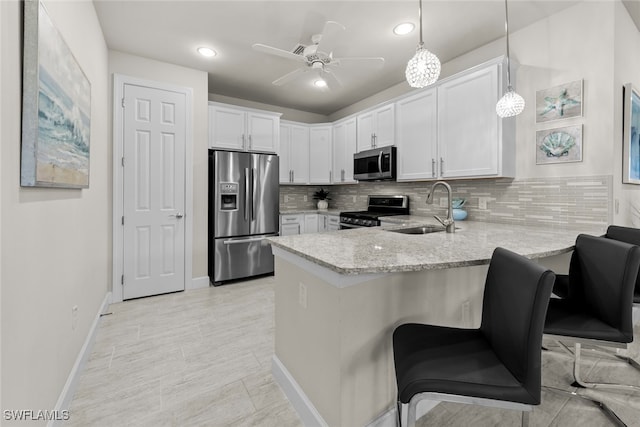 kitchen with stainless steel appliances, sink, kitchen peninsula, decorative light fixtures, and white cabinets