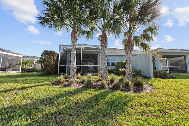 rear view of house featuring a sunroom and a lawn