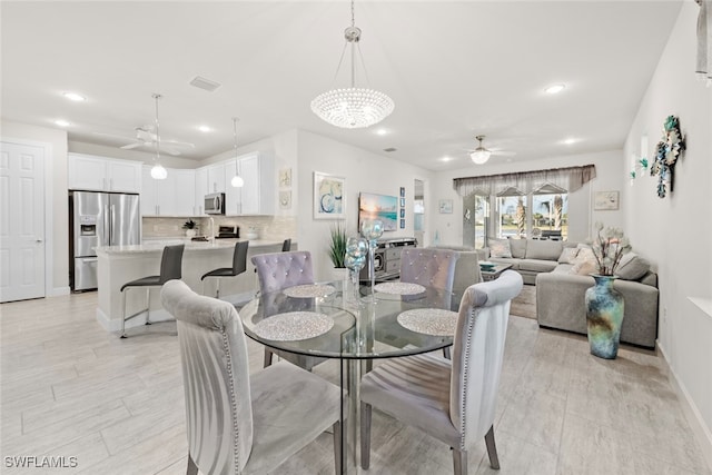 dining space with ceiling fan with notable chandelier