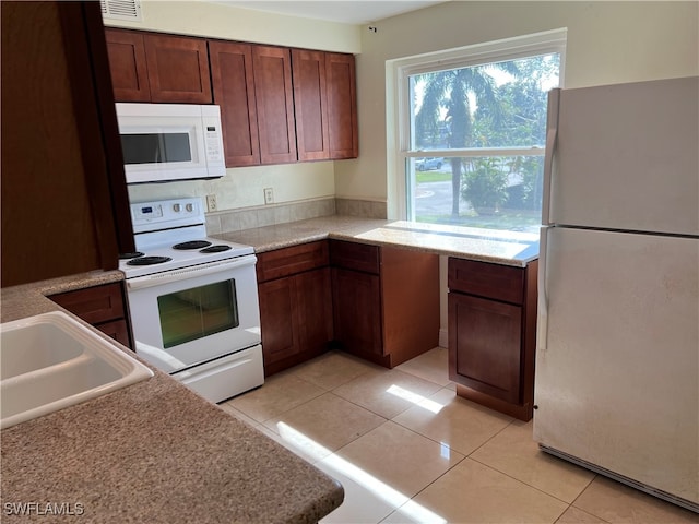 kitchen featuring white appliances, sink, and light tile patterned flooring