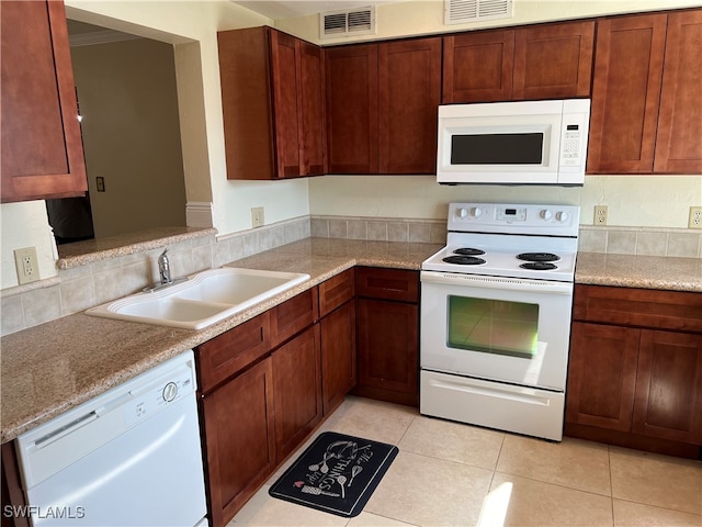 kitchen with light tile patterned floors, white appliances, light stone countertops, and sink